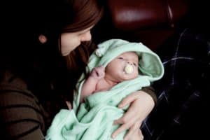 woman holding baby green blanket pink dummy