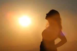 a woman is looking at the sky during a sunset